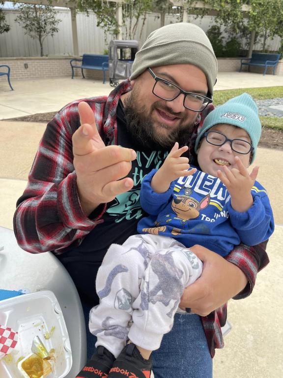 Young boy with father smiling and pointing at camera