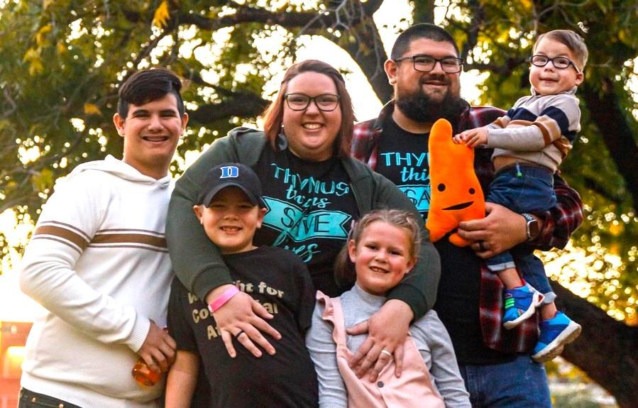 A family of mom, dad and four children hug and smile