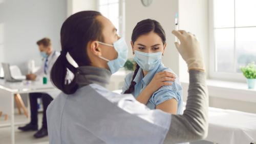 Woman getting a shot in her upper arm from healthcare provider.