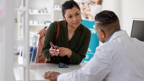 Woman shows pharmacist her phone.