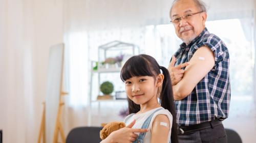 Older man and kid show off their band aids after getting vaccine.